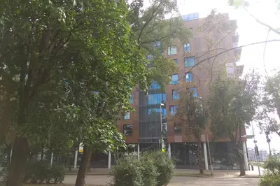 a large brick building with trees in front of it at Slucko Central Studio Apartment near River in Vilnius