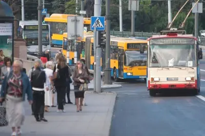 a group of people walking on a city street with buses at Slucko Central Studio Apartment near River in Vilnius