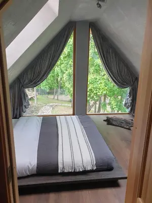 a bed in a room with a large window at Stone house in Prapuntai