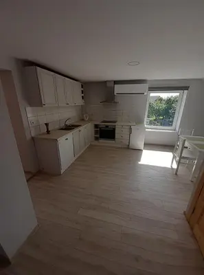 a kitchen with white cabinets and a large window at VĖJO16 in Biržai