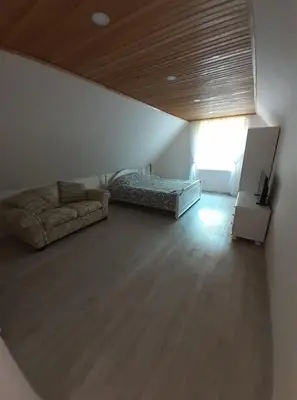 a room with a bed and a couch and a window at VĖJO16 in Biržai