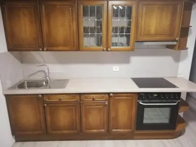 a kitchen with wooden cabinets and a sink and a stove at Vėjo 16 in Biržai
