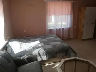a bedroom with a bed and a couch and a window at VĖJO16 in Biržai