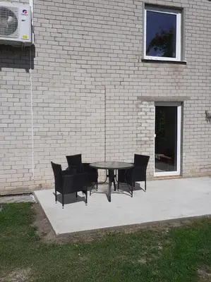 a picnic table and chairs in front of a brick building at VĖJO16 in Biržai