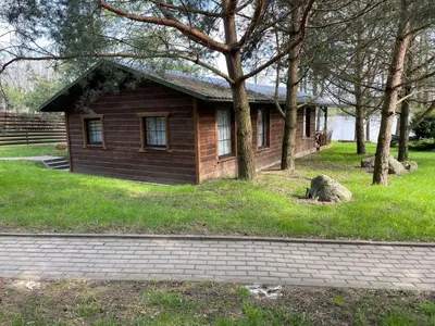 a small wooden house in a field with trees at Atostogų būstas in Kurėnai