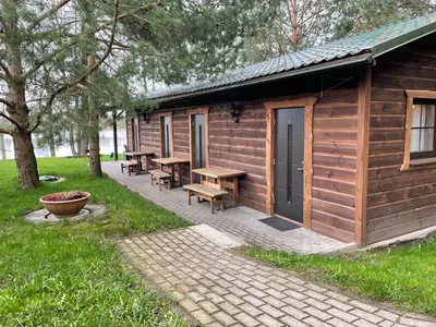 a wooden cabin with tables and benches in the grass at Atostogų būstas in Kurėnai