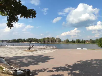 a park with a statue next to a body of water at Ramus poilsis prie Širvintų marių in Širvintos