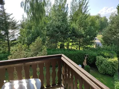 a balcony with a table and a view of a garden at Ramus poilsis prie Širvintų marių in Širvintos