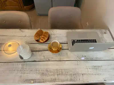 a table with a laptop and bread and a cup of coffee at Cosy and peaceful apartment in Kaunas