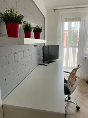 an office with a desk with a chair and a tv at Lake apartaments in Ignalina