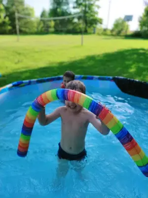 a young man in a swimming pool with a inflatable hose at Sodyba Basapėdė in Bijutiškis