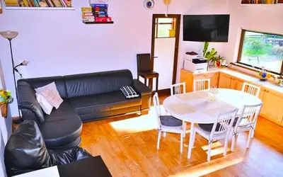a living room with a black leather couch and a table at Sodyba Basapėdė in Bijutiškis