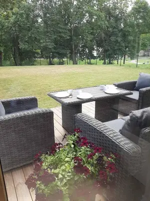 a patio with a table and wicker chairs and flowers at Mazoji vila in Birštonas