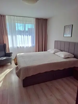 a bedroom with a bed and a chair and a window at Apartamentai Vytauto 16 in Druskininkai