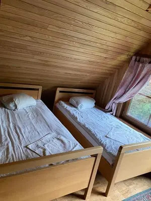 two beds in a wooden room with a window at Šeimyninis namelis nr.1 in Kurėnai