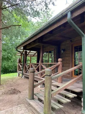 a log cabin with a wooden porch and a fence at Šeimyninis namelis nr.2 in Kurėnai