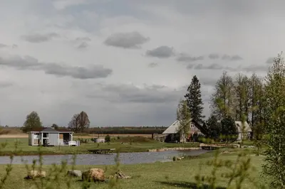a house in a field next to a river at Vienkiemio Oazė - Autentiškas Kluonas in Galvokai