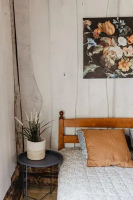 a bedroom with a bed with a table and a painting at Vienkiemio Oazė - Autentiškas Kluonas in Galvokai