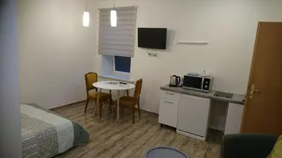 a small room with a bed and a table and a kitchen at Laisvės 50D in Kaunas