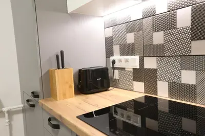 a kitchen with black and white tiles on the wall at Comfy 2 Room Apartment - Free Parking - 350Mbps WiFi - Netflix in Kaunas