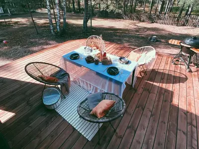 a table and chairs on a deck with a blue table and chairs at Peledos troba in Žiūrai