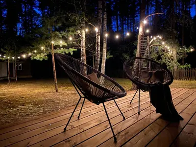 a person sitting in a hammock on a deck at night at Peledos troba in Žiūrai