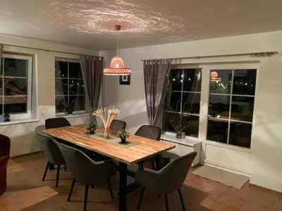 a dining room with a table and chairs and windows at Peledos troba in Žiūrai