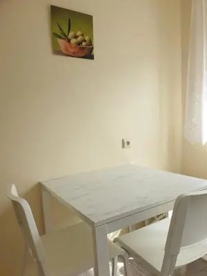 a white dining room table with two chairs and a painting at Lima C in Druskininkai