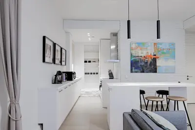 a white kitchen with a counter and stools at Buddha Luxury Apartment Kaunas city centre in Kaunas