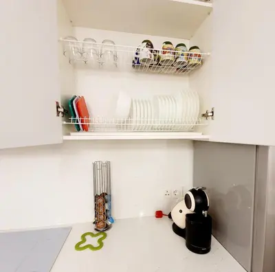 a kitchen with white cabinets and a shelf with dishes at Home sweet home in Radviliškis