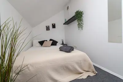 a white bedroom with a bed with a blanket at The house black in Vilnius