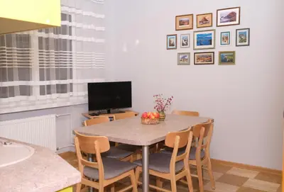 a dining room with a table with chairs and a television at Alma B&B in Kalvarija