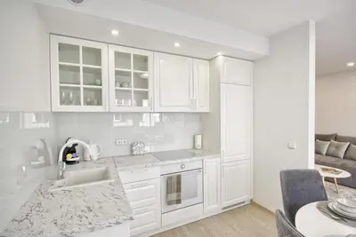 a kitchen with white cabinets and a sink and a table at Liepų Apartments in Druskininkai