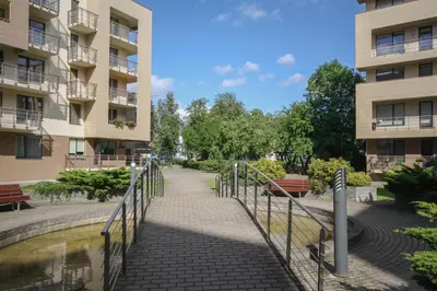 a walkway between two buildings next to a body of water at Liepų Apartments in Druskininkai