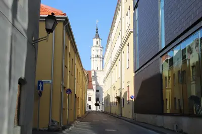 an empty city street with a clock tower in the background at Old Town Apartment with a separate entrance in Kaunas
