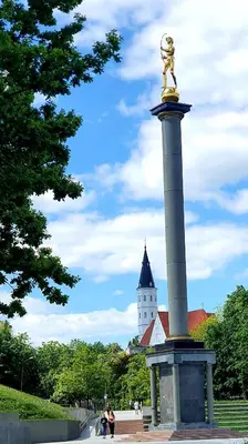 a statue in front of a building with a tower at Apartment next to Cathedral of Saints Peter & Paul in Šiauliai