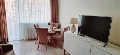 a living room with a television and a table with chairs at Apartment next to Cathedral of Saints Peter & Paul in Šiauliai