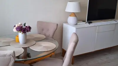 a dining room with a glass table and two chairs and a television at Apartment next to Cathedral of Saints Peter & Paul in Šiauliai