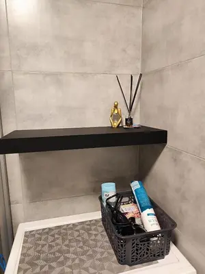 a bathroom with a basket of toiletries on a shelf at Monica Apartments in Panevėžys