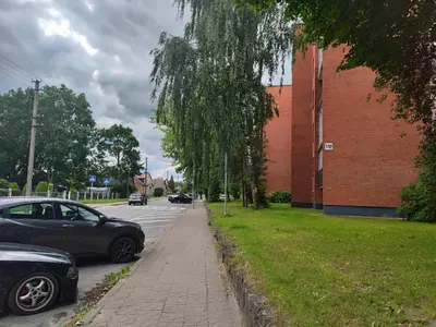 a car parked on a street next to a brick building at Monica Apartments in Panevėžys