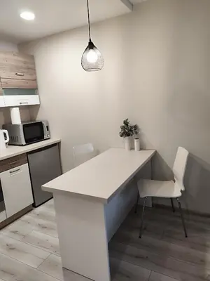 a kitchen with a white counter and white chairs at Monica Apartments in Panevėžys