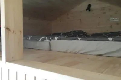 a bed in a room with a wooden floor at Mėnulės pirtelė in Sudeikiai