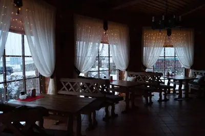 a dining room with wooden tables and large windows at Meškių dvarkiemis in Šiauliai