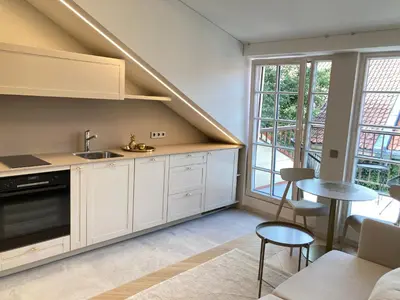 a kitchen with white cabinets and a sink and a table at COME2rest - Subaciaus 5 in Vilnius