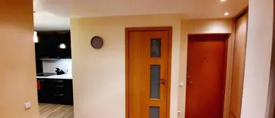a kitchen with a door and a clock on a wall at M&M Apartment VIII Self CHECK-IN in Panevėžys