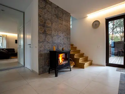 a living room with a fireplace and a staircase at Pine Home in Druskininkai