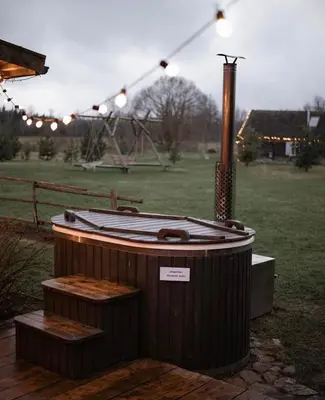 a hot tub sitting in a field with lights at Vienkiemio Oazė - Namelis Prie Šermukšnio in Galvokai