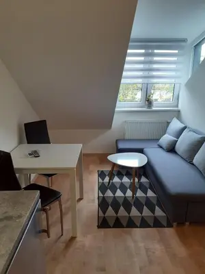 a living room with a blue couch and a table at Attic rooms at Laisves avenue in Kaunas