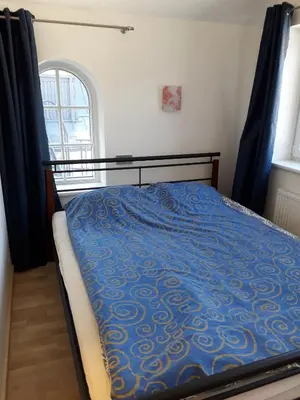 a bedroom with a bed with a blue comforter and a window at Attic rooms at Laisves avenue in Kaunas