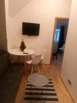 a living room with a table and a tv on a wall at Attic rooms at Laisves avenue in Kaunas